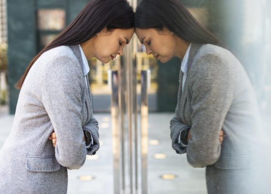 side-view-businesswoman-leaning-her-head-against-glass-door